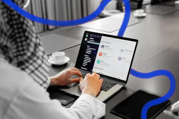 A person typing on a laptop at a meeting-room table