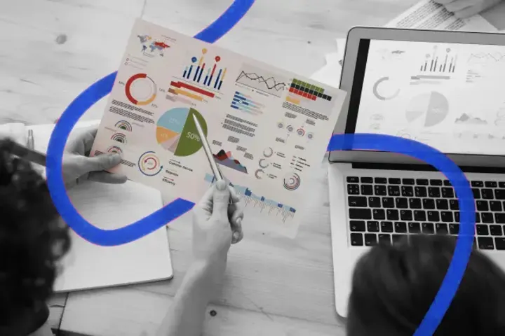 Printed charts being reviewed beside a laptop