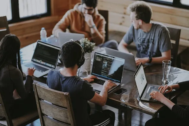 A team of developers working on laptops around a shared table